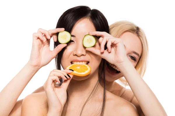 Duas mulheres étnicas diferentes com laranja e pepino — Fotografia de Stock