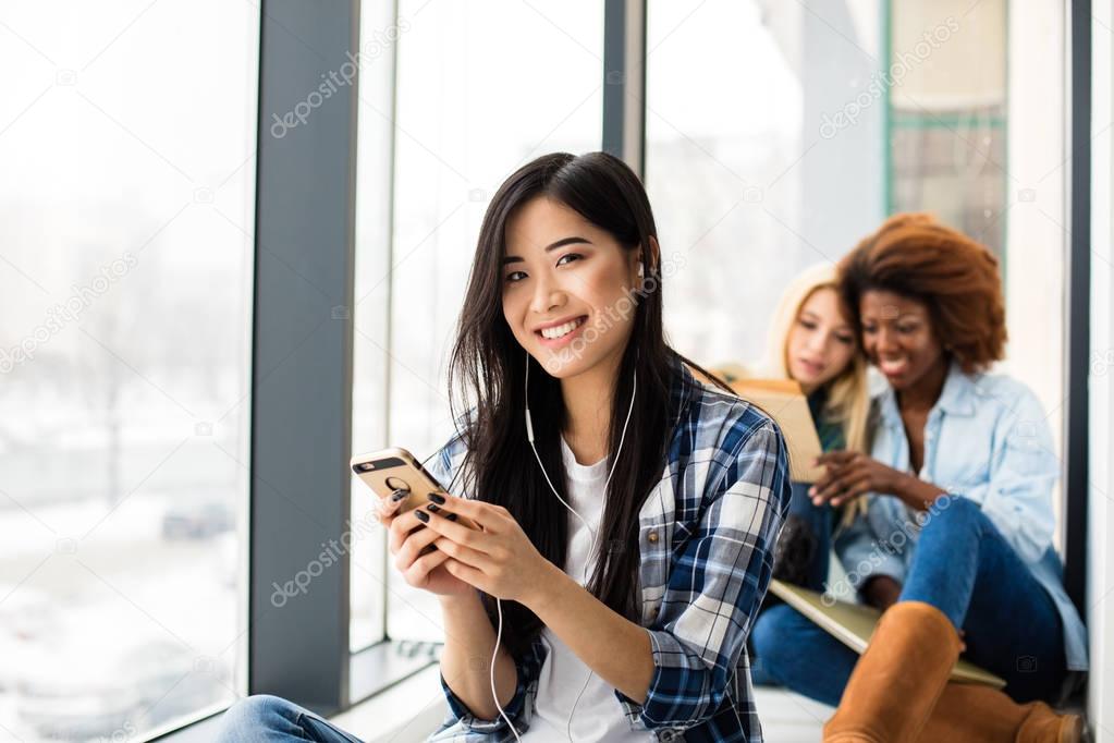 close up of asian girl listening music and other friends behind