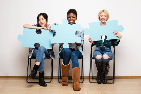 группа из трех разных женщин, сидящих на стульях с головоломкой
 