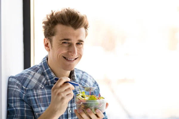 Handsome young man eating salad — Stock Photo, Image