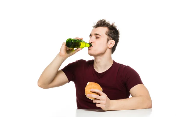 Joven bebiendo cerveza y comiendo hamburguesa — Foto de Stock