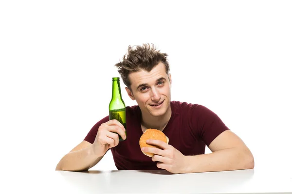 Joven bebiendo cerveza y comiendo hamburguesa — Foto de Stock