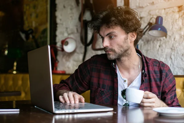 Mladý muž s notebookem v popředí v hospodě — Stock fotografie