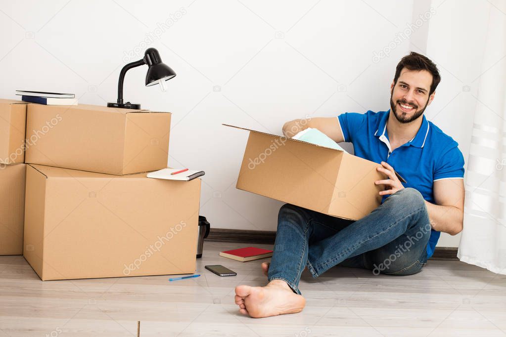man lying on the floor with packing boxes 