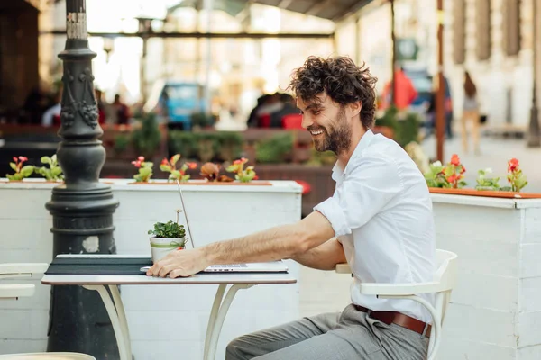 Guapo elegante hombre trabajando fuera en una mesa de café — Foto de Stock