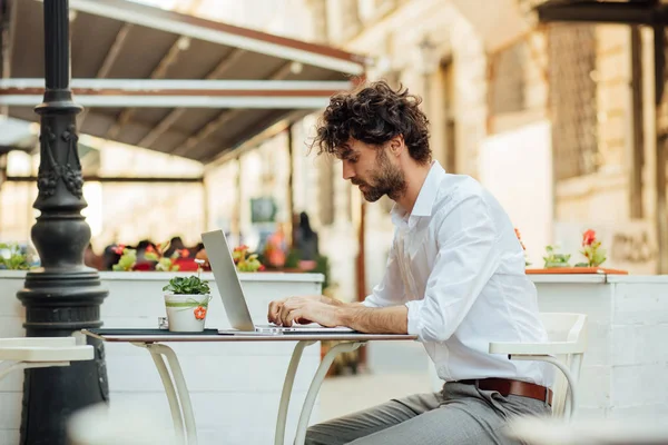 Guapo elegante hombre trabajando fuera en una mesa de café — Foto de Stock