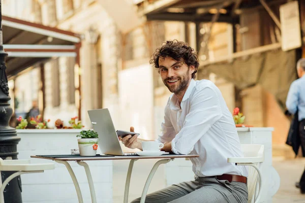 Guapo elegante hombre trabajando fuera en una mesa de café — Foto de Stock