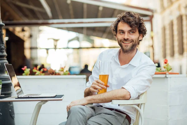 ผู้ชายหล่อที่งดงามนั่งอยู่ข้างนอกระเบียง ดื่มเบียร์ — ภาพถ่ายสต็อก