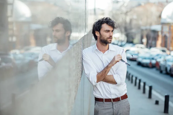 Bello uomo elegante stanting fuori contro un muro grigio — Foto Stock