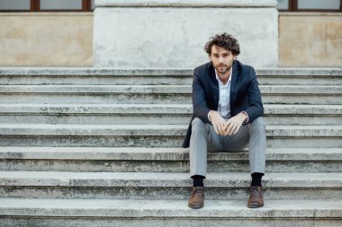 Yetişkin ve zarif bir adam dışında merdivenlerde oturan