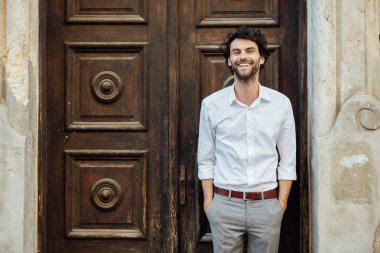 ahşap bir kapı önünde ayakta olgun adam