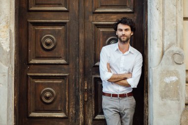 ahşap bir kapı önünde ayakta olgun adam
