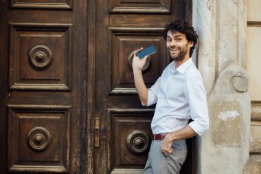 ahşap bir kapı önünde ayakta olgun adam