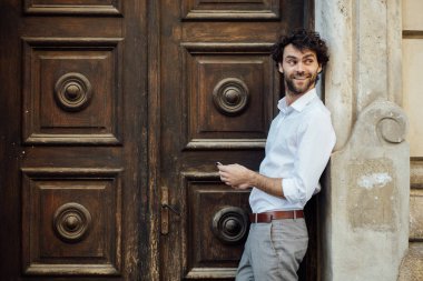 ahşap bir kapı önünde ayakta olgun adam