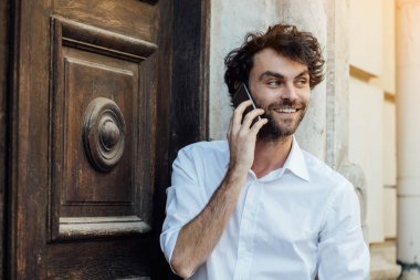 ahşap bir kapı önünde ayakta olgun adam