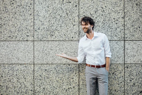 Bello uomo elegante stanting fuori contro un muro grigio — Foto Stock