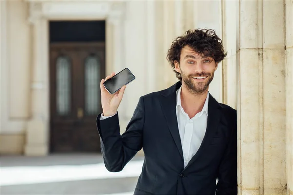 Guapo elegante hombre de pie fuera contra una columna de un ol — Foto de Stock