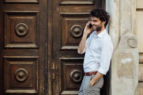 Mature man standing in front of a wooden door — Stock Photo, Image