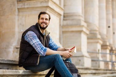 bir klasik BI ile binada arkasında sahip sırt çantası ile genç adam