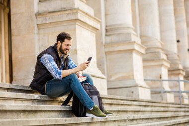 bir klasik BI ile binada arkasında sahip sırt çantası ile genç adam