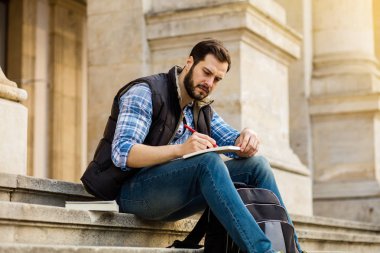 bir klasik BI ile binada arkasında sahip sırt çantası ile genç adam