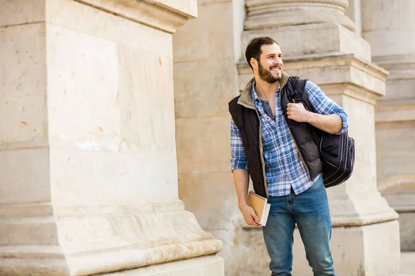 Junger Mann mit Rucksack, der hinter einem klassischen Gebäude mit — Stockfoto