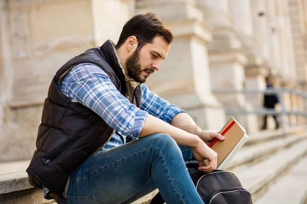 Jeune homme avec sac à dos ayant derrière un bâtiment classique avec bi — Photo