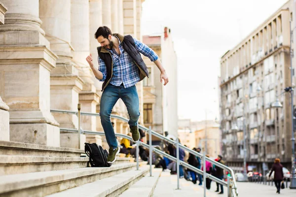 Jovem com mochila tendo atrás de um edifício clássico com bi — Fotografia de Stock