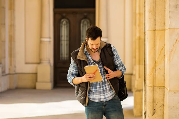 Junger Mann mit Rucksack, der hinter einem klassischen Gebäude mit — Stockfoto