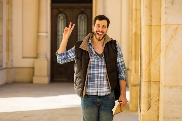 Junger Mann mit Rucksack, der hinter einem klassischen Gebäude mit — Stockfoto