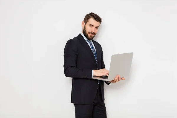 Eleganta mannen i kostym med slips håller en laptop på vita bak — Stockfoto