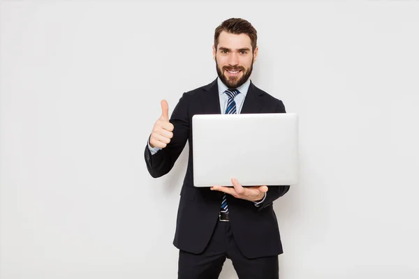 Eleganta mannen i kostym med slips håller en laptop på vita bak — Stockfoto