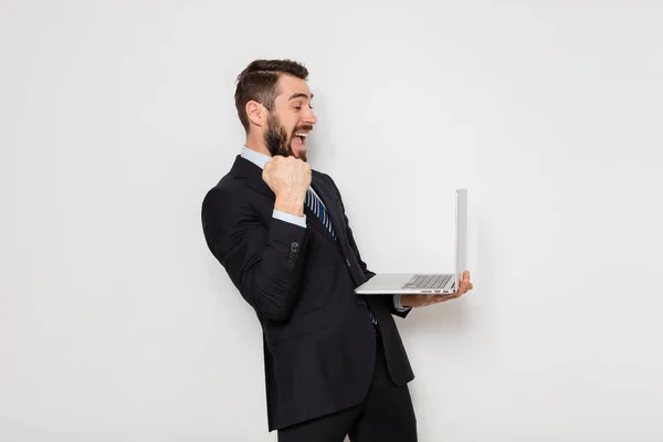 Elegante uomo in giacca e cravatta con in mano un computer portatile su sfondo bianco — Foto Stock