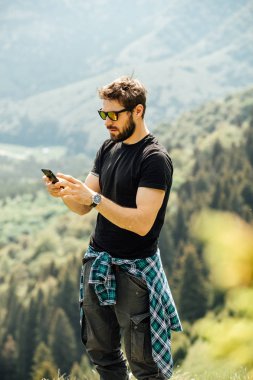 kayaların üzerinde duran ve cep telefonunu kontrol dostum