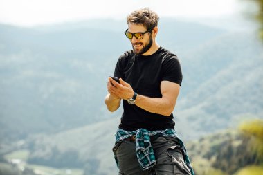 kayaların üzerinde duran ve cep telefonunu kontrol dostum