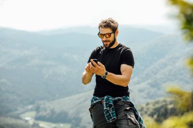 kayaların üzerinde duran ve cep telefonunu kontrol dostum