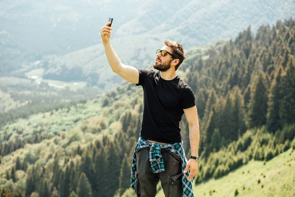 男は岩の上に立って、彼の携帯電話をチェック — ストック写真