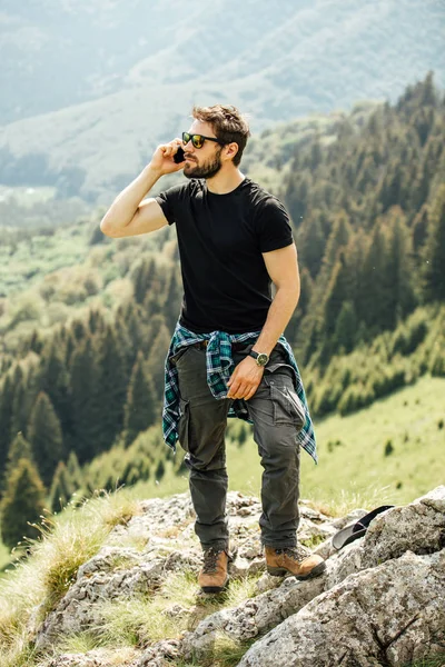 Hombre viajando en las montañas y hablando en el teléfono móvil —  Fotos de Stock