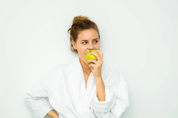 Mulher em toalha de banho branca comendo e maçã — Fotografia de Stock