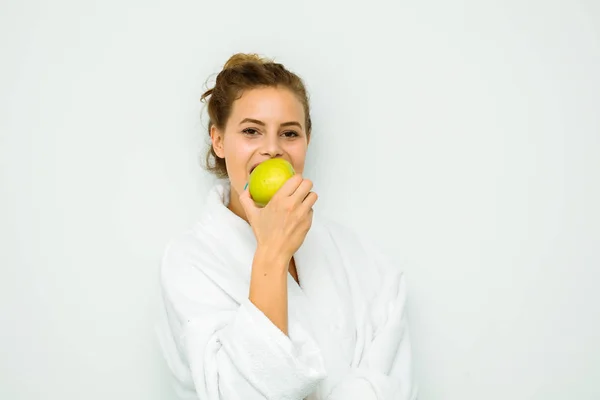 Mulher em toalha de banho branca comendo e maçã — Fotografia de Stock