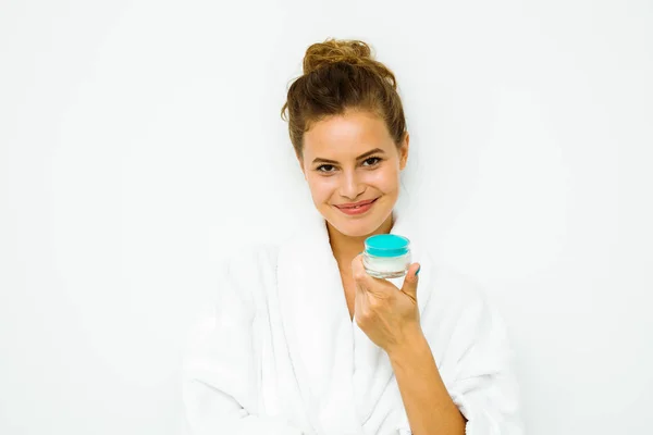Donna in asciugamano bianco con in mano una crema per la pelle — Foto Stock