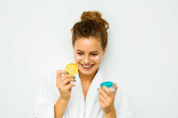 Femme en serviette de bain blanche tenant une crème pour la peau — Photo