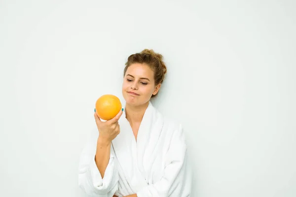 Mulher em toalha de banho branca com uma grande toranja — Fotografia de Stock