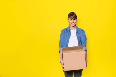 karton kutu hareket ile sarı zemin üzerinde duran güzel kadın