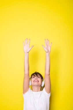 beyaz kulaklık üzerinde izole sarı arka plan işaret ile genç ve güzel kadın