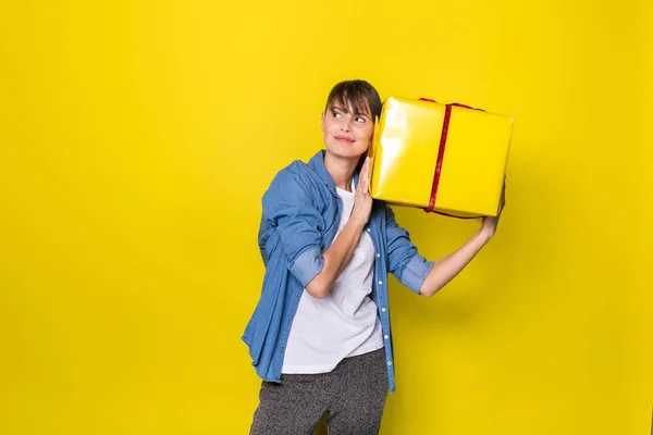 Mujer Joven Feliz Escuchando Una Caja Regalo Amarilla Para Adivinar — Foto de Stock