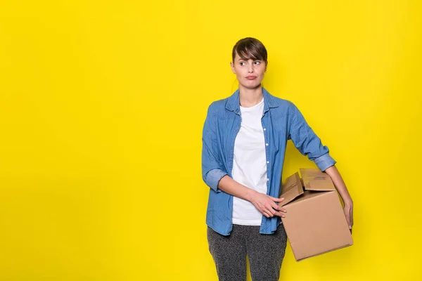 Mooie Vrouw Staande Gele Achtergrond Met Bewegende Kartonnen Doos — Stockfoto