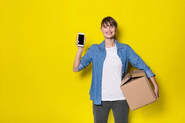 Ładna Kobieta Stojąc Żółtym Tle Ruchu Karton Pomocą Jej Telefon — Zdjęcie stockowe