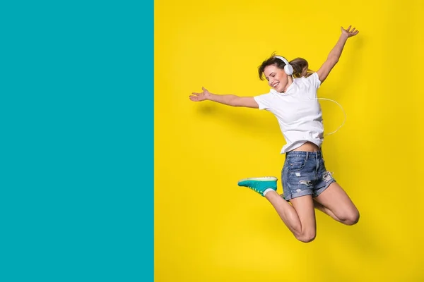 Молодая Счастливая Женщина Слушает Музыку Прыгает Большой Улыбкой Желтом Фоне — стоковое фото