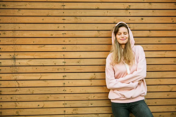 Cool young woman in pink hoodie on wooden background — Stock Photo, Image